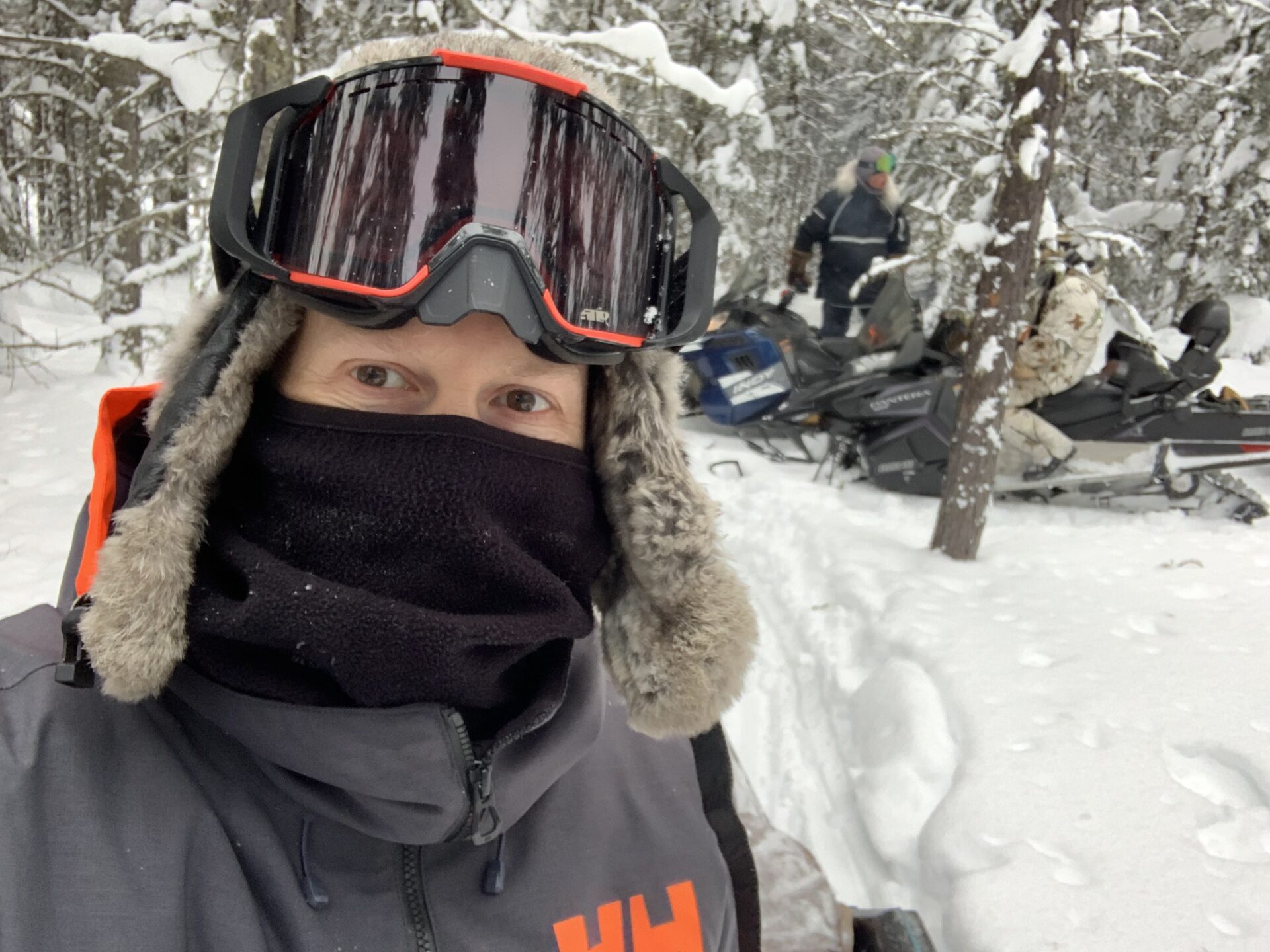 Jeff Newman taking a selfie during a break after driving a snowmobile in a heavily wooded and snowed forest